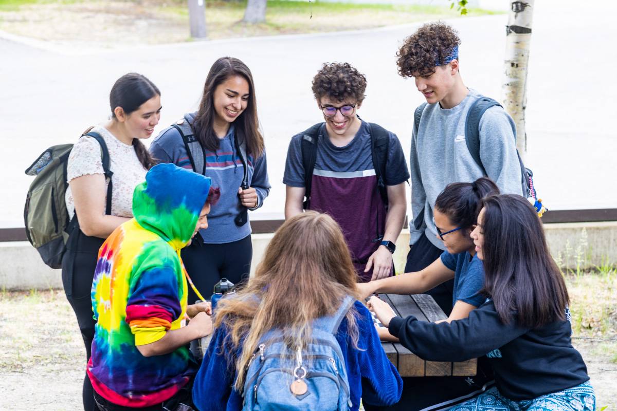 һФһг Students gather at a picnic table outside the Wood Center on the Fairbanks Troth Yeddha' campus
